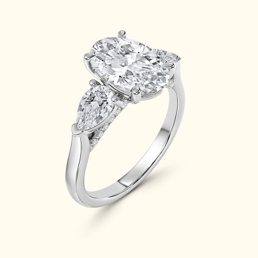 Three-stone engagement ring featuring an oval diamond flanked by two pear-shaped diamonds.