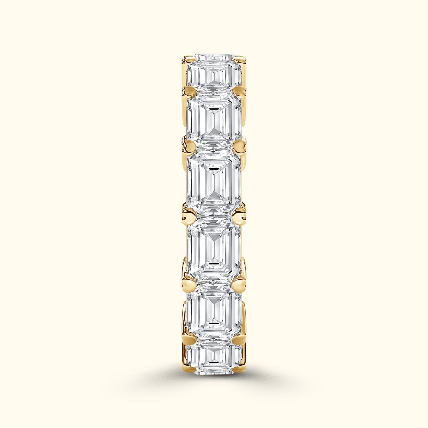 Gold band set with alternating emerald-cut diamonds, vertically oriented.