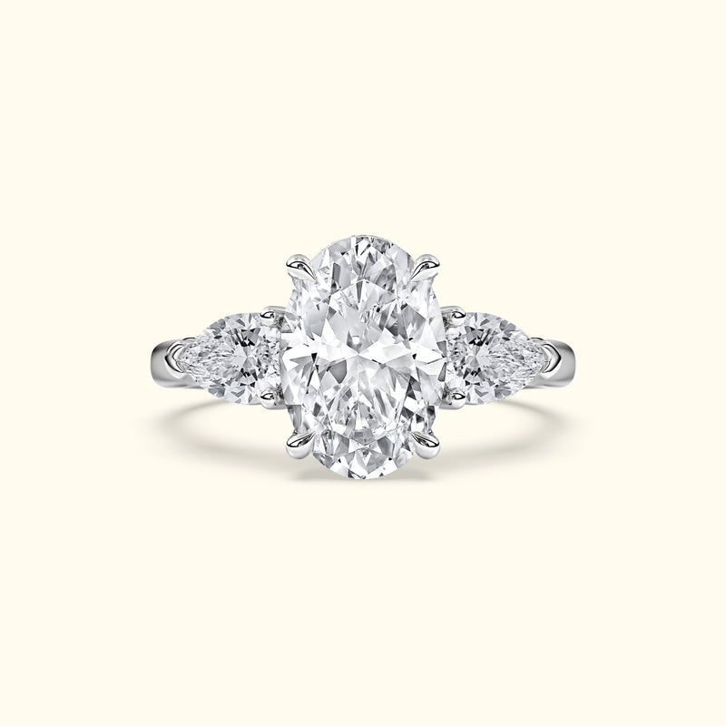 Elegant three-stone engagement ring featuring a large oval diamond flanked by two pear-shaped diamonds.