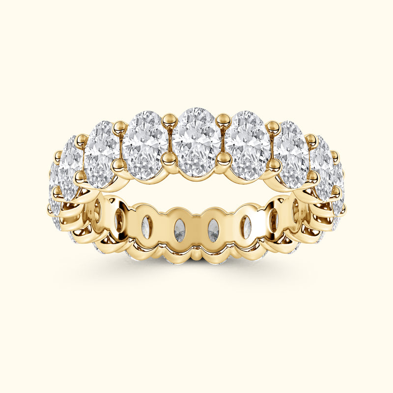 Gold band ring set with multiple oval-shaped, sparkling clear gemstones.