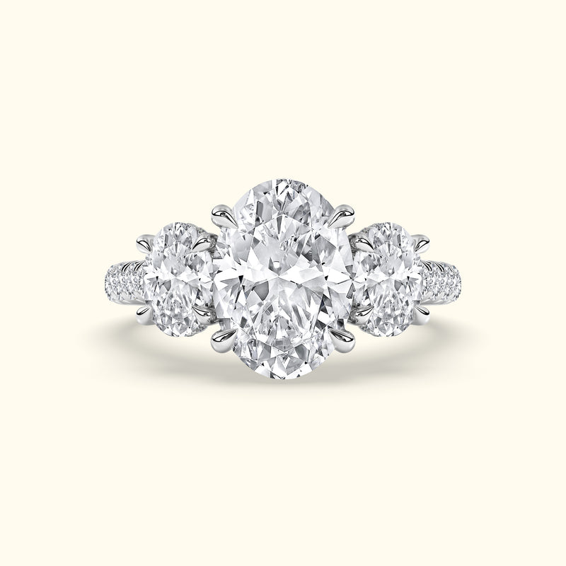 Three-stone diamond ring featuring a central oval diamond flanked by two round diamonds.