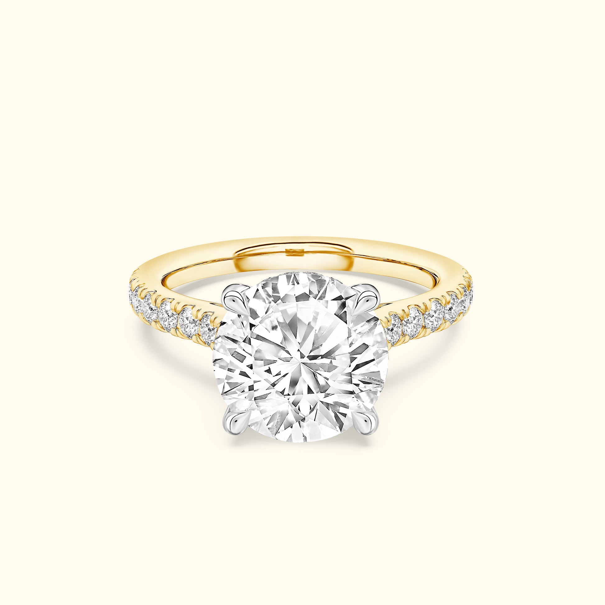 A sparkling diamond engagement ring with a yellow gold band and pave set diamonds.