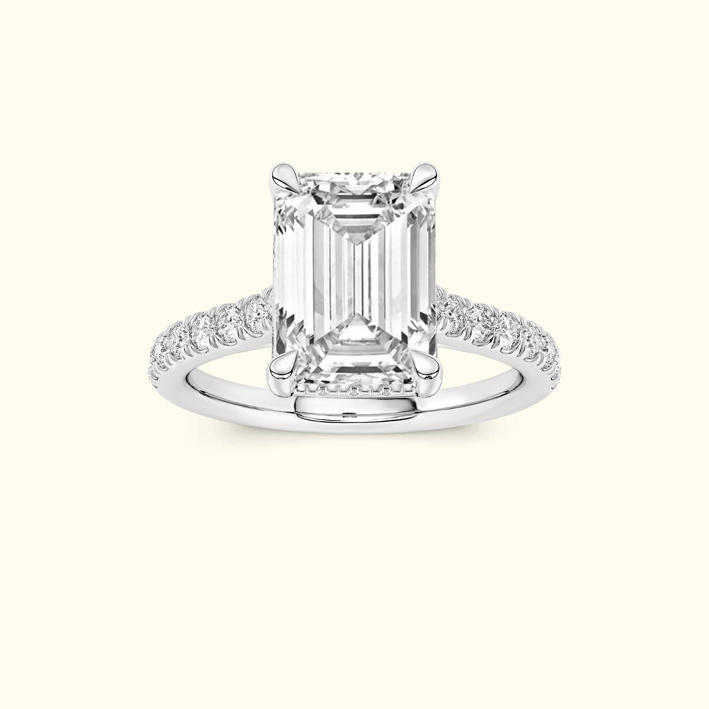 Emerald-cut diamond ring with pave-set diamond band on a light background.