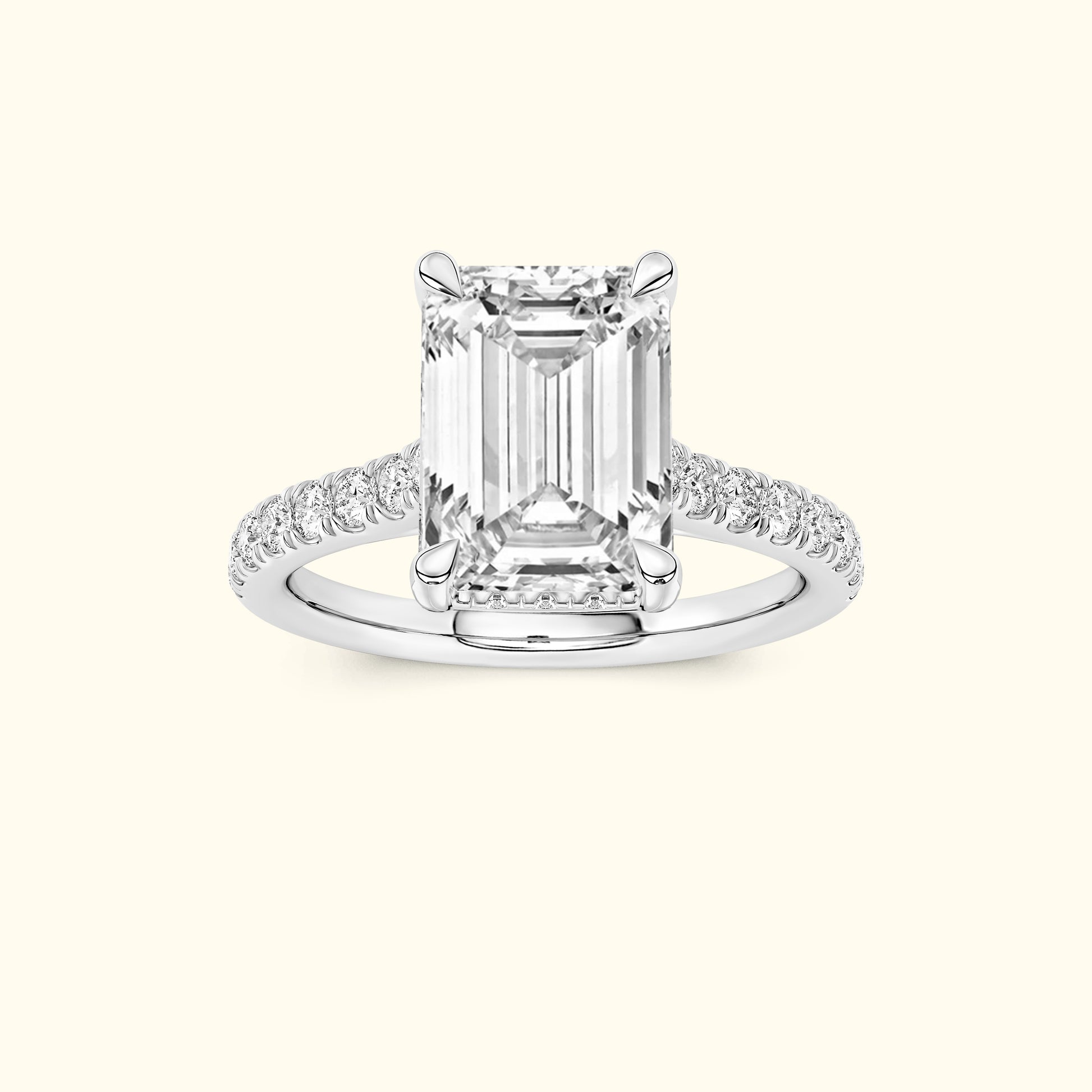Emerald-cut diamond ring with pave-set diamond band on a light background.