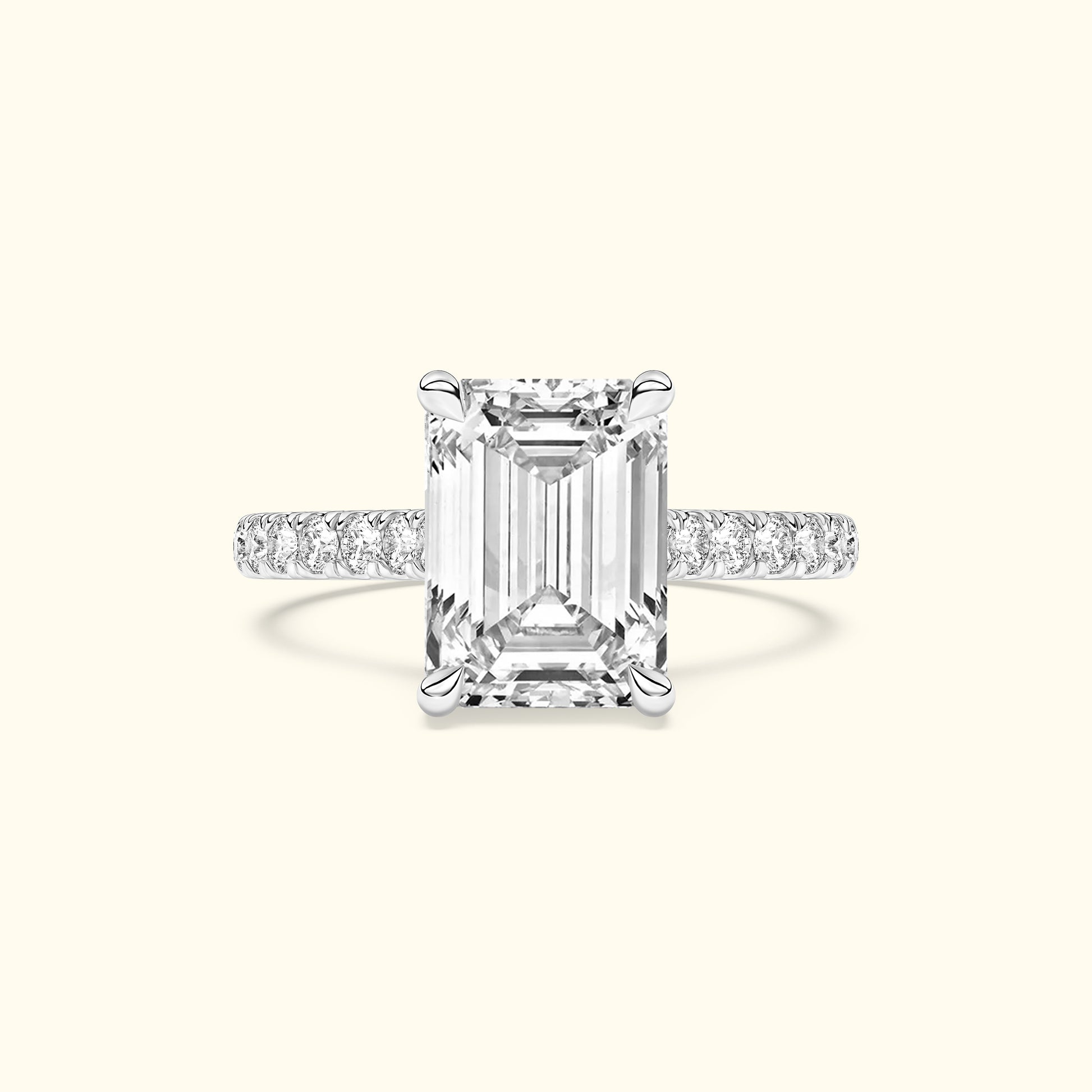 Emerald-cut diamond ring with a delicate band adorned with smaller diamonds.