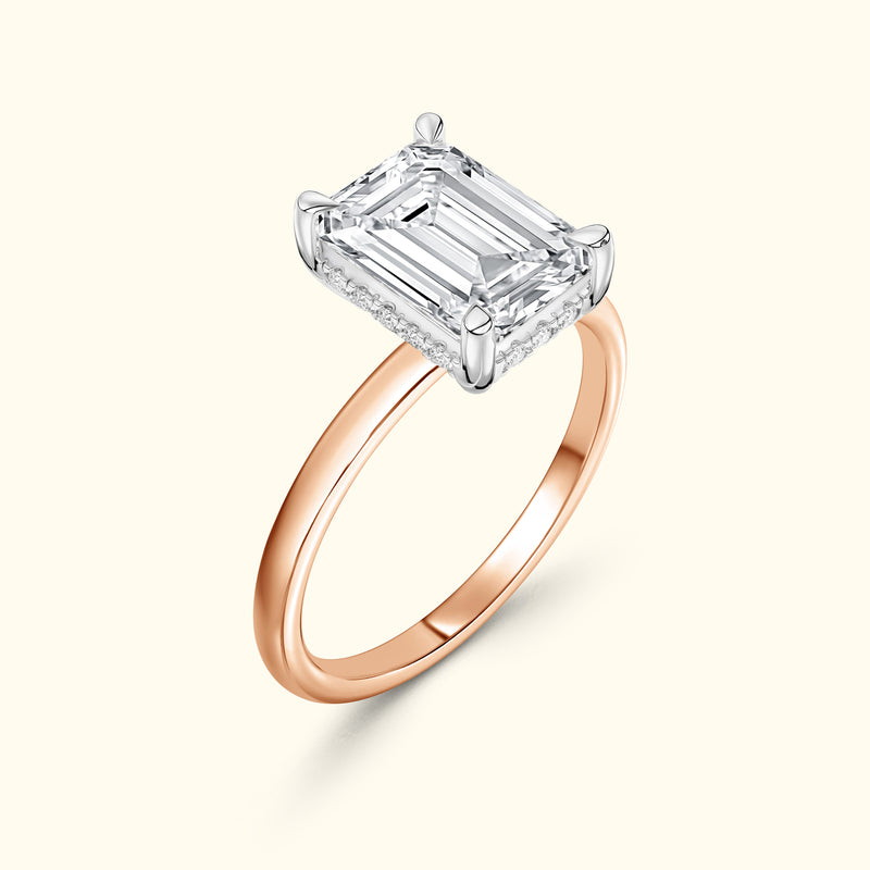 Emerald-cut diamond ring with a rose gold band and pave diamond accents.