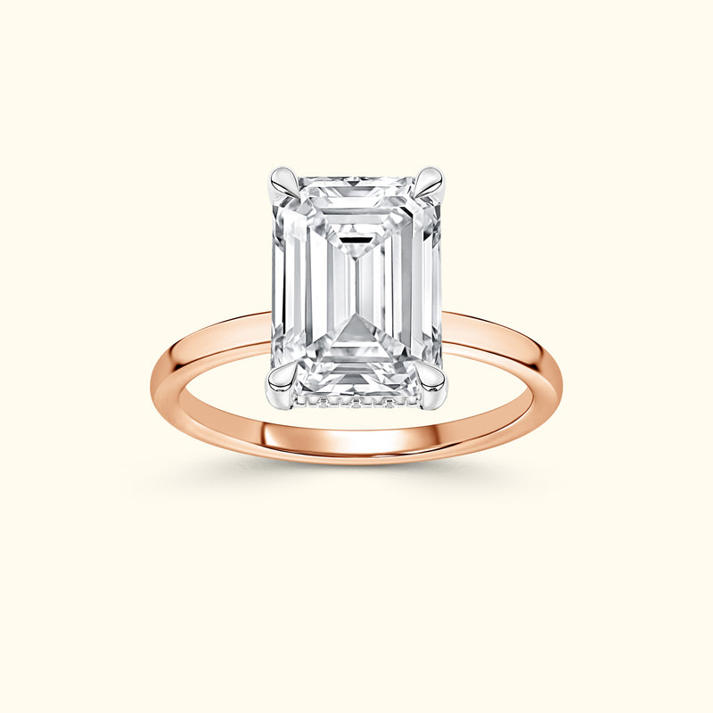 Emerald-cut diamond ring set in a slender rose gold band.