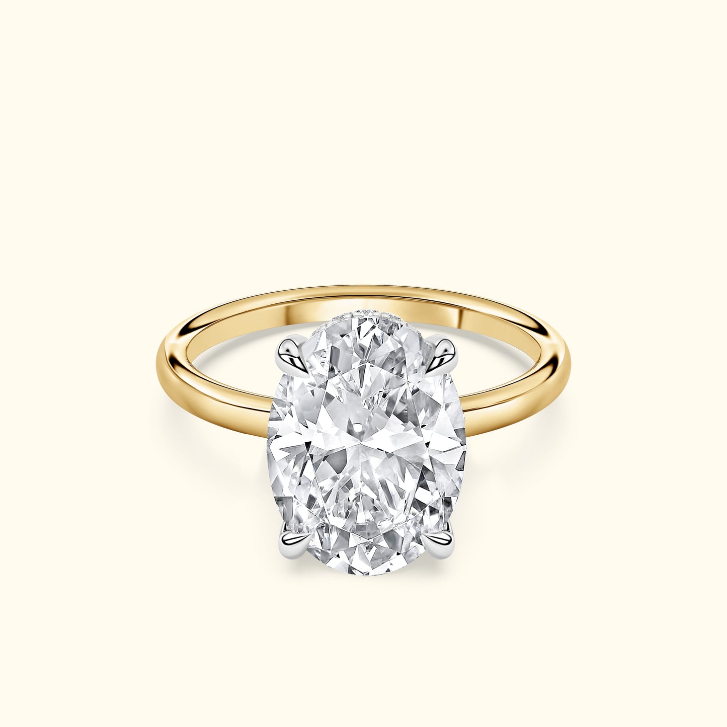 Oval diamond engagement ring with a gold band and silver prongs on a light background.