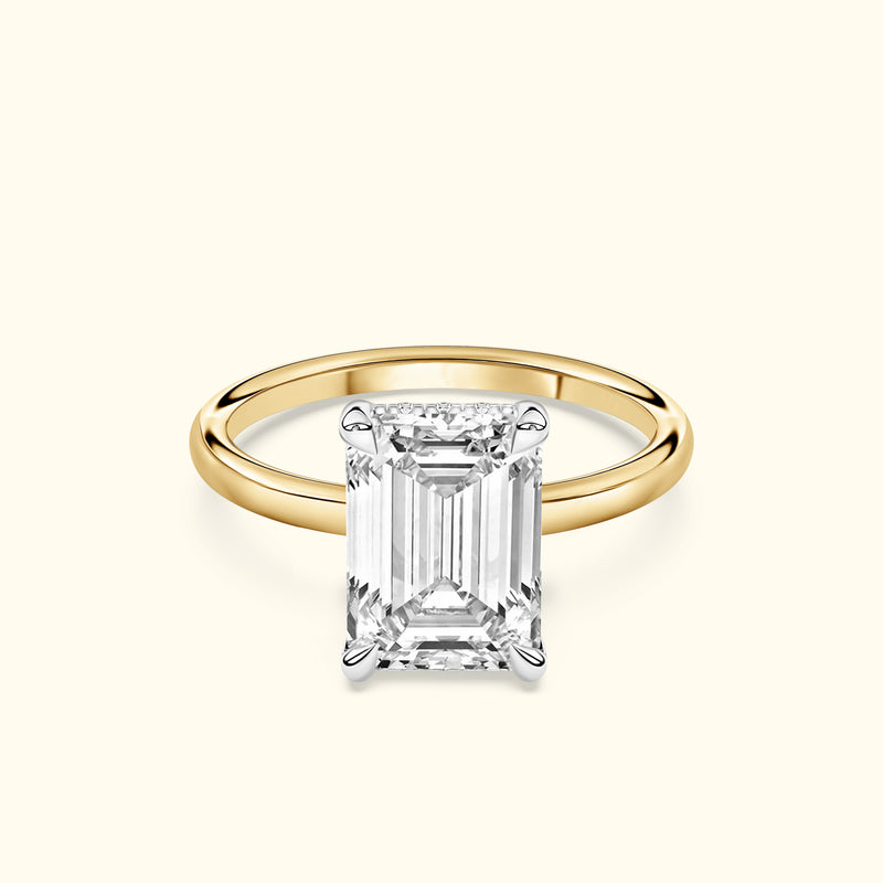 A gold engagement ring featuring a large emerald-cut diamond centerpiece.