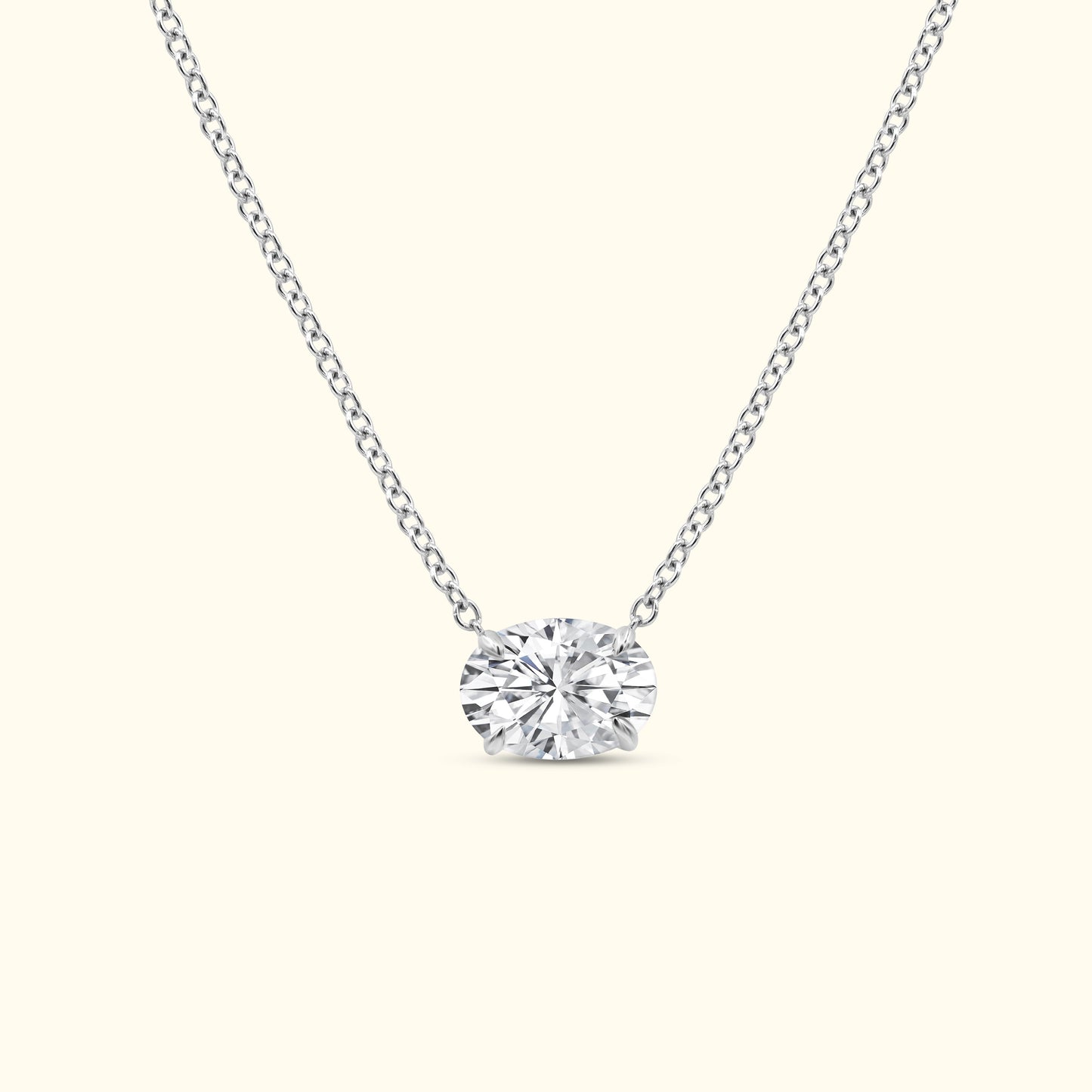 A elegant silver necklace featuring a central oval diamond pendant.