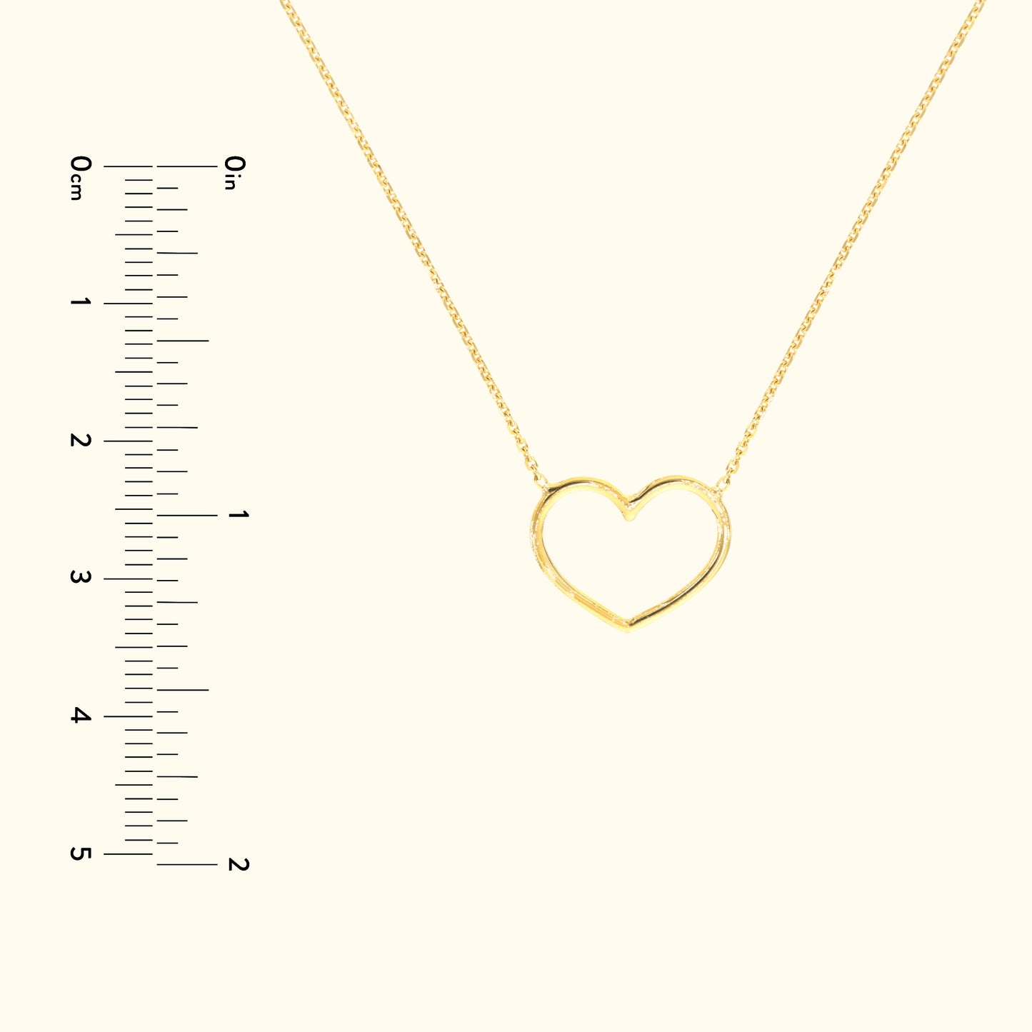 Gold heart-shaped necklace on a delicate chain with a ruler for scale.