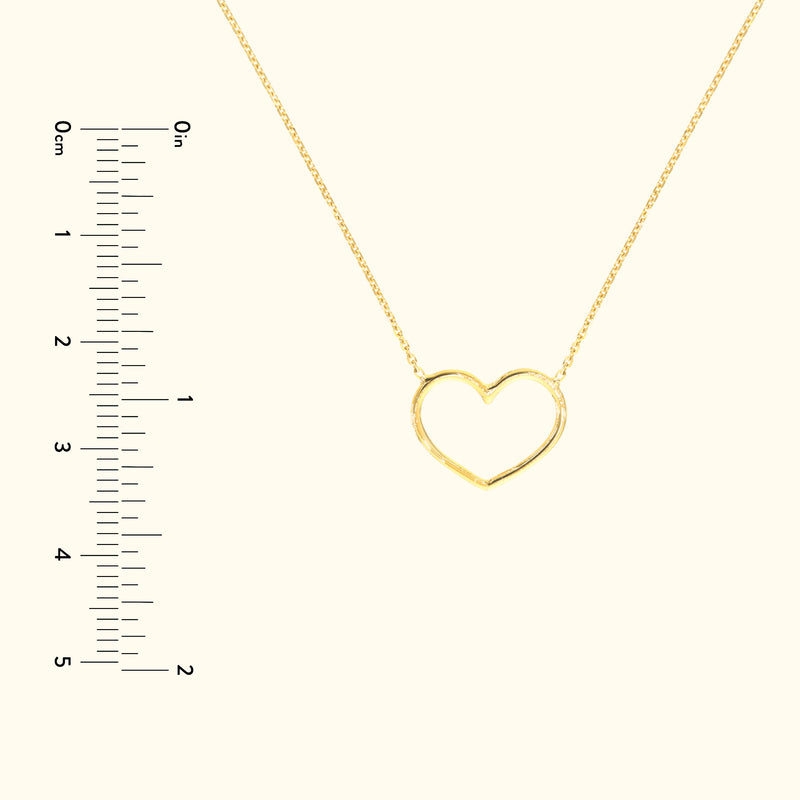 Gold heart-shaped necklace on a delicate chain with a ruler for scale.