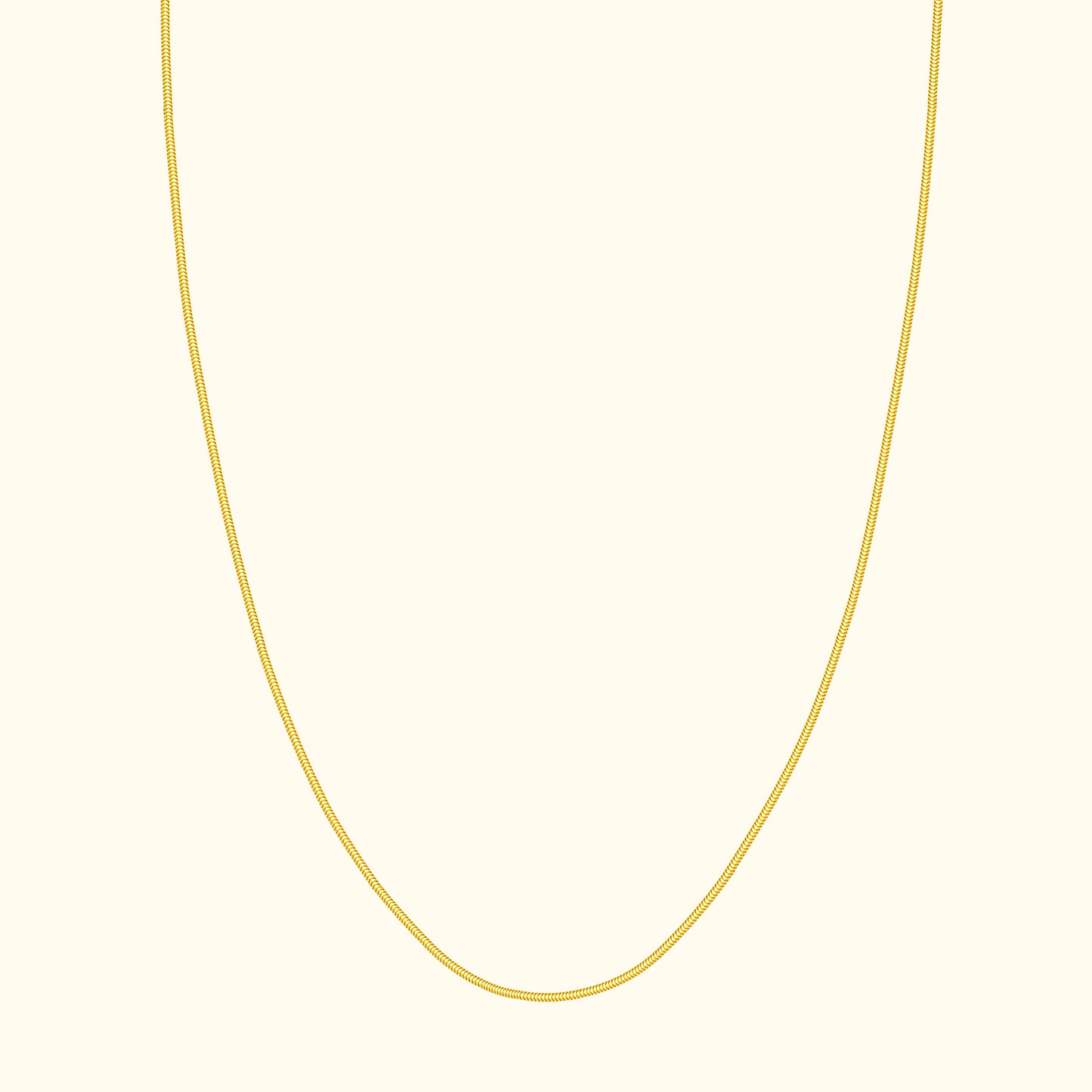 Thin gold necklace elegantly draped against a cream background.