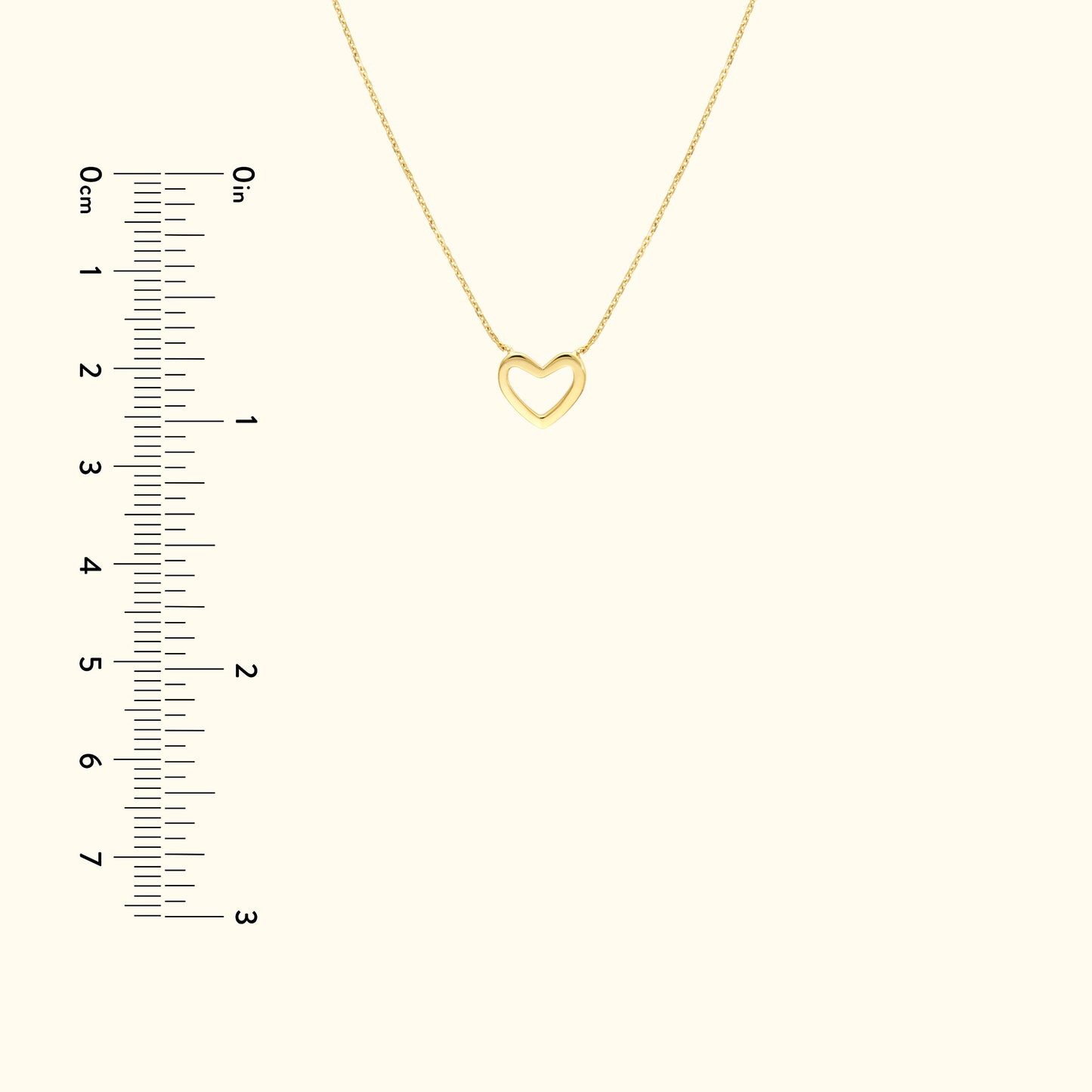 Delicate gold heart pendant necklace on a light background with a ruler for size reference.
