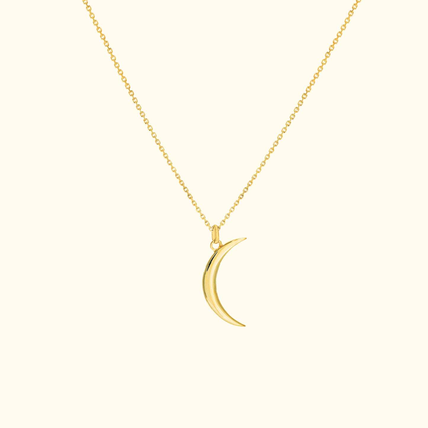 Gold crescent moon pendant on a delicate chain necklace against a light background.