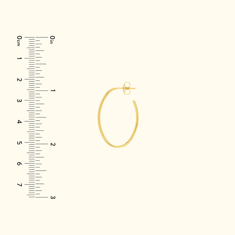 Gold hoop earring with a secure clasp, next to a ruler for size reference.
