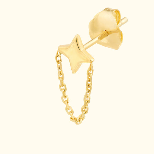 Gold star stud earring with a delicate chain connecting to a floral backing.