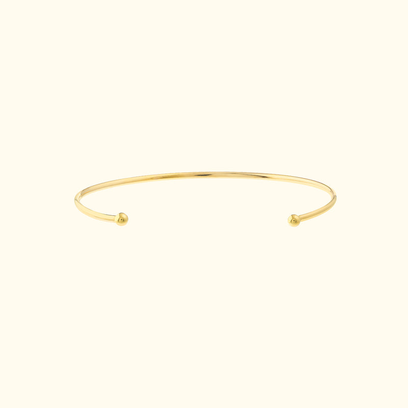 Simple gold cuff bracelet with open ends and rounded tips.