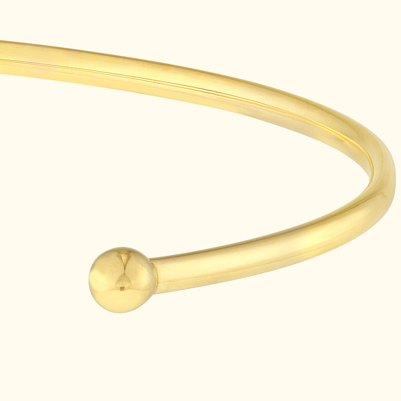 Minimalist gold cuff bracelet with rounded end.