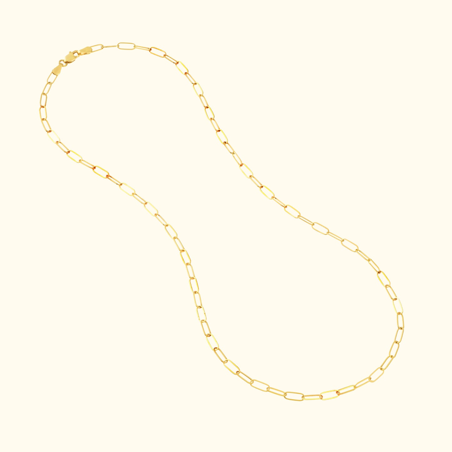 Gold chain necklace with elongated, linked design on a light background.