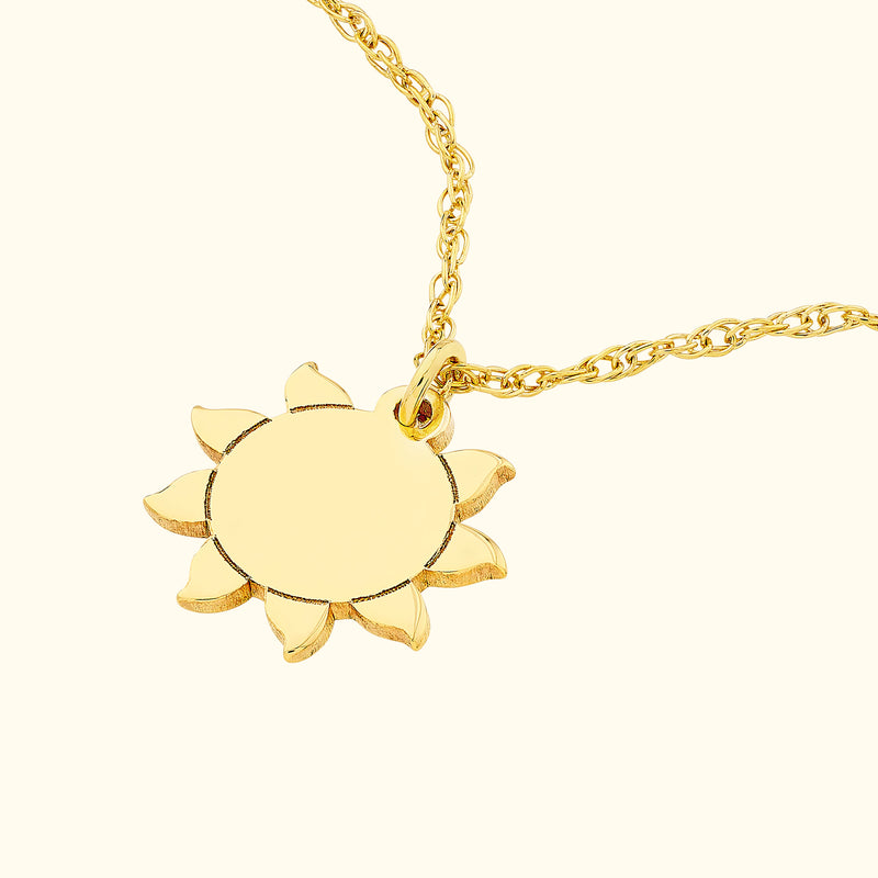Gold sunflower pendant on a delicate chain against a light background.