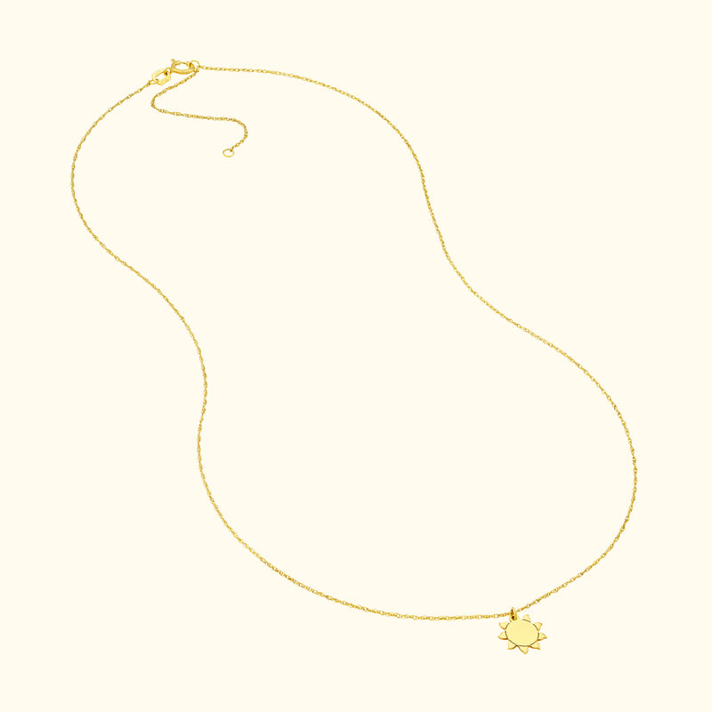 Delicate gold necklace with a sun-shaped pendant, suspended on a thin chain.