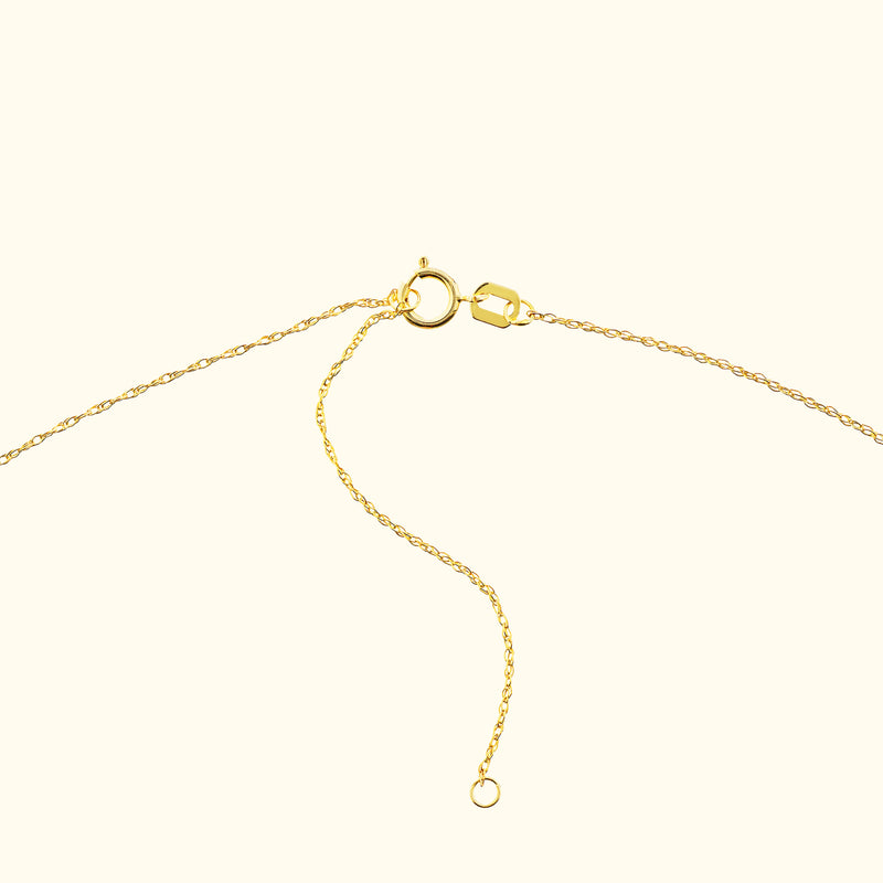 Golden necklace chain clasp with a delicate chain, resting on a light background.