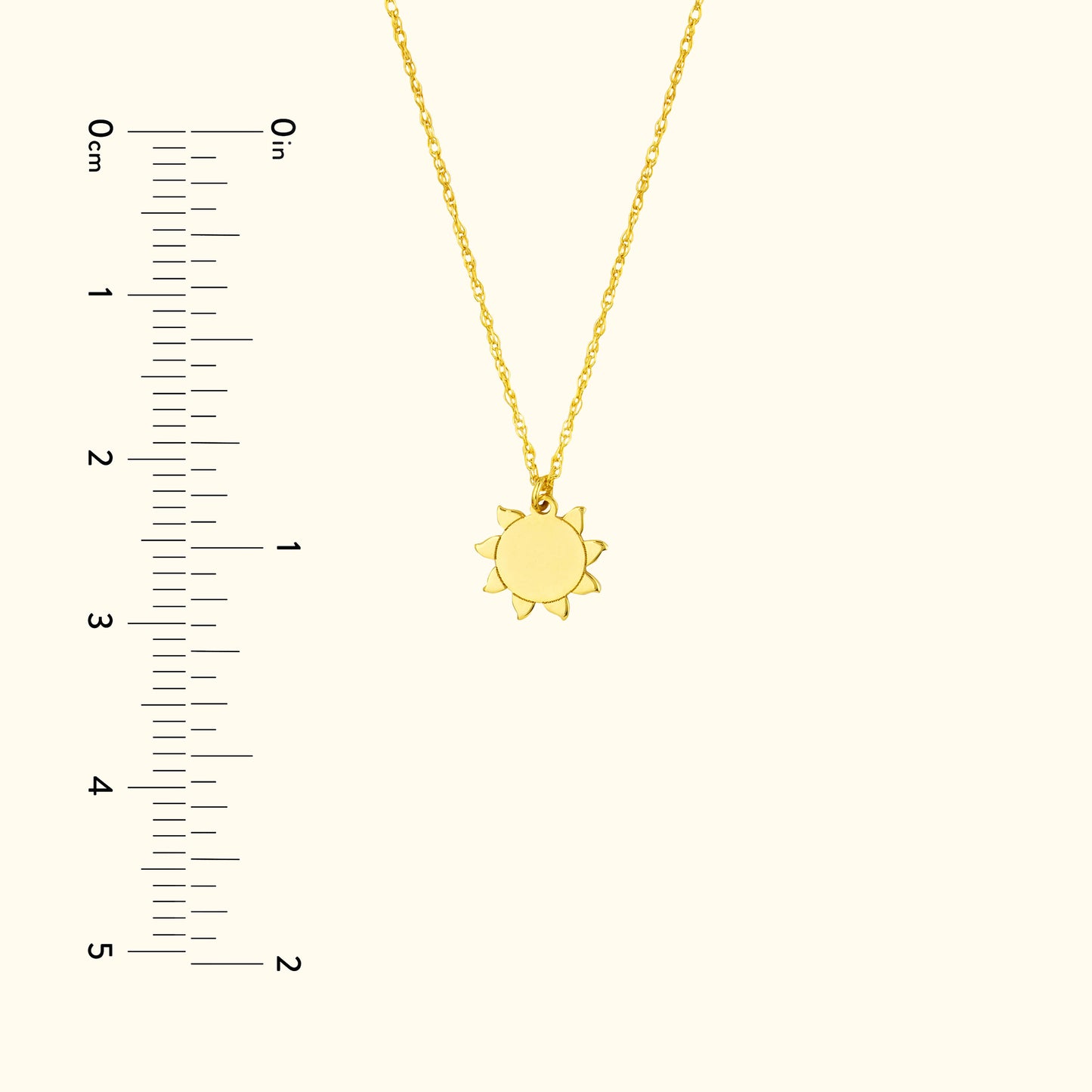 Gold sun pendant necklace on a delicate chain, with a ruler for size reference.