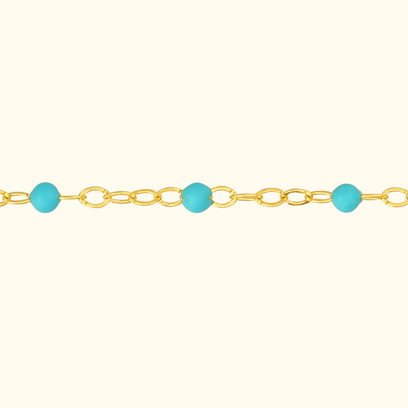 Gold chain necklace with turquoise beads evenly spaced throughout.