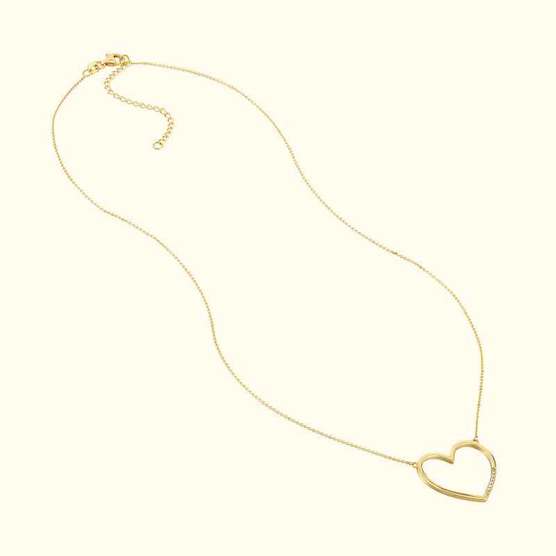 Gold heart-shaped necklace on a delicate chain against a light background.