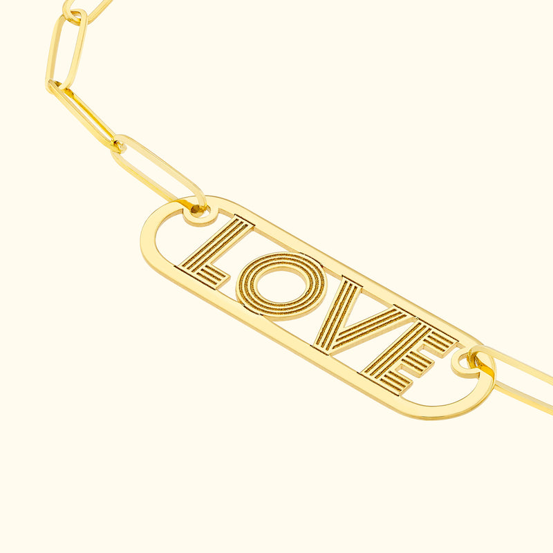 Gold bracelet featuring a rectangular charm with the word "LOVE" engraved.