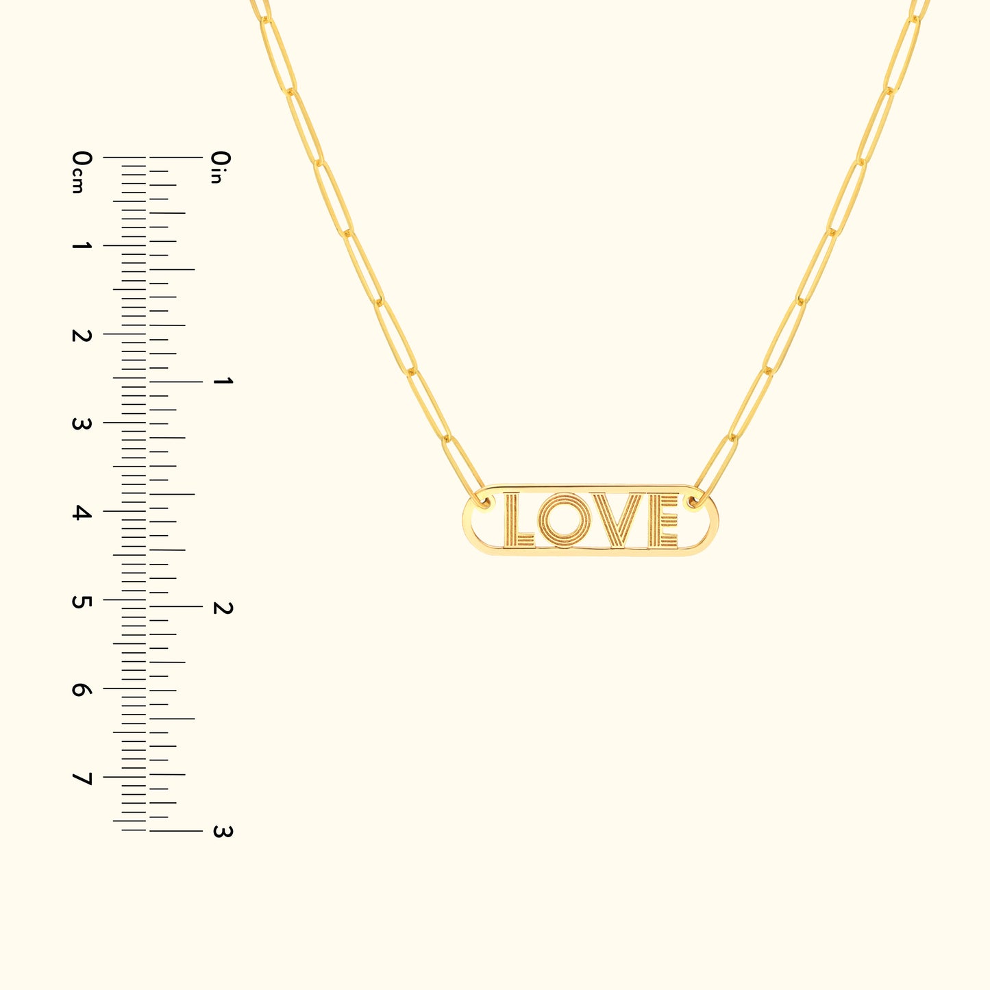 Gold necklace featuring a pendant that reads "LOVE," accompanied by a ruler for size reference.