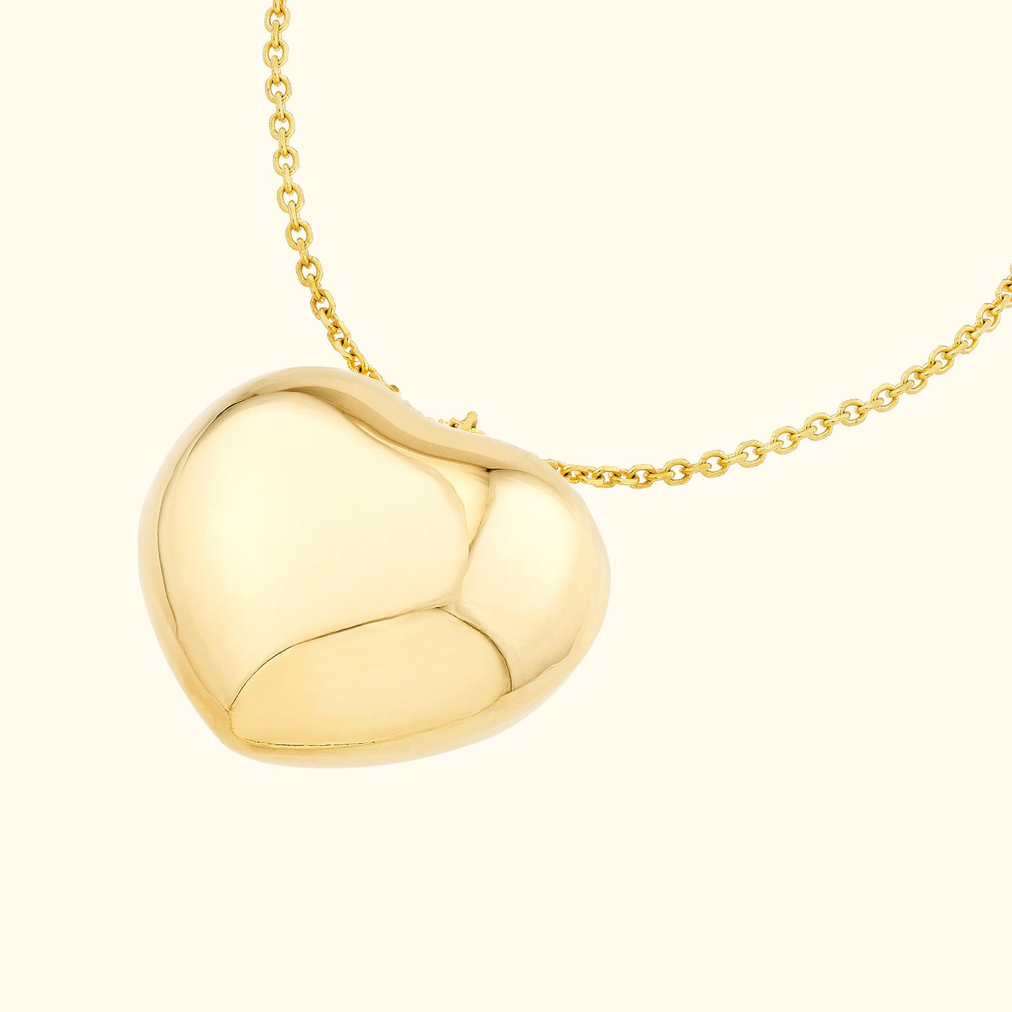 Gold heart-shaped locket pendant hanging from a fine chain necklace.