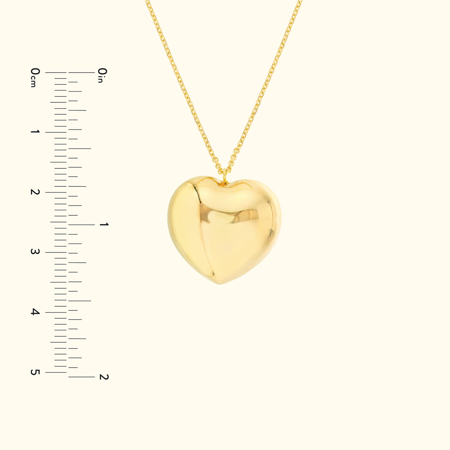 Gold heart-shaped pendant with a chain, displayed alongside a ruler for scale.