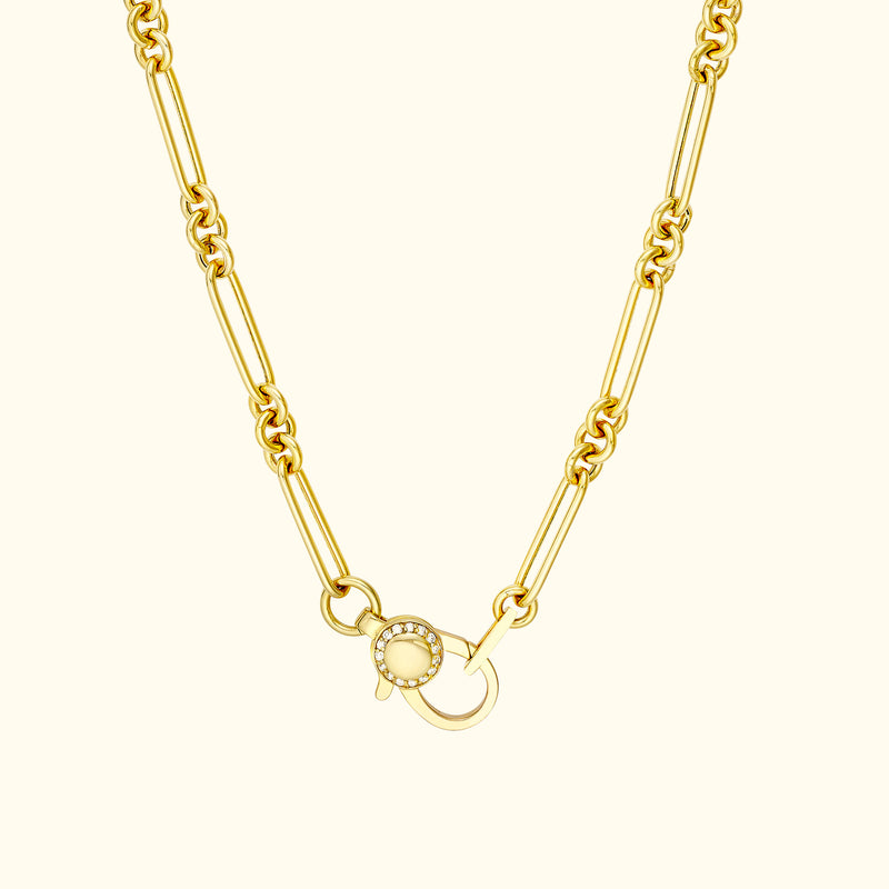 Gold chain necklace with a decorative clasp featuring a small bead.