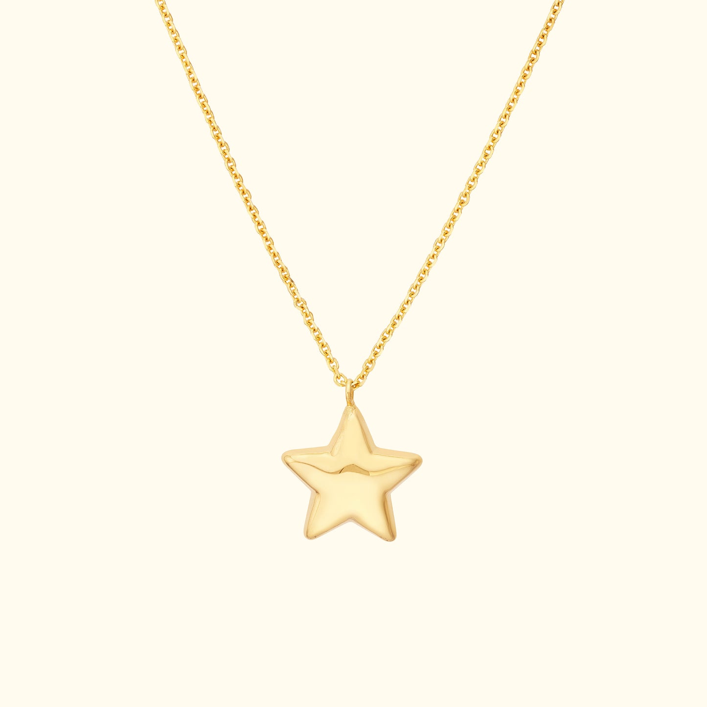 Gold star pendant necklace on a delicate chain against a light background.