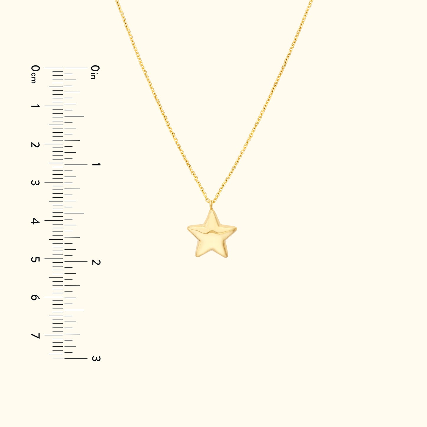 Gold star pendant on a delicate chain with a ruler for size reference.
