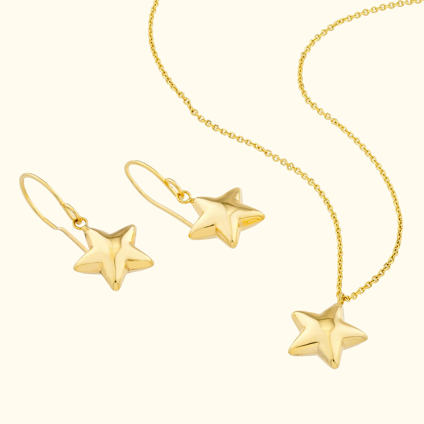 Gold star-shaped earrings and matching necklace on a light background.