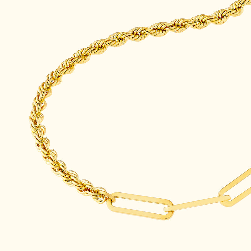 Twisted gold bracelet with a smooth, elegant design on a light background.