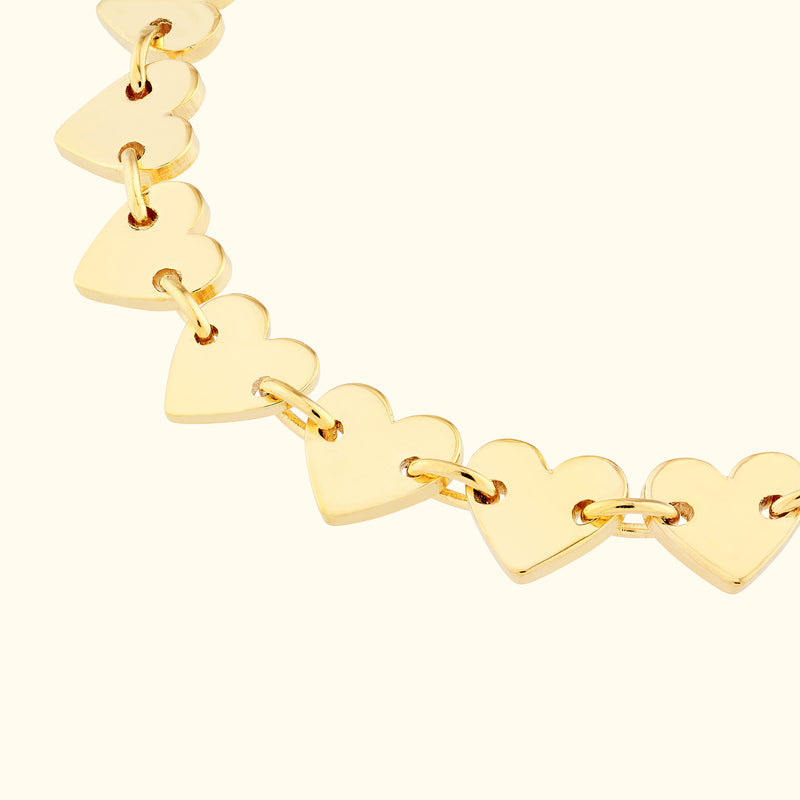 Gold heart-shaped link bracelet against a light background.