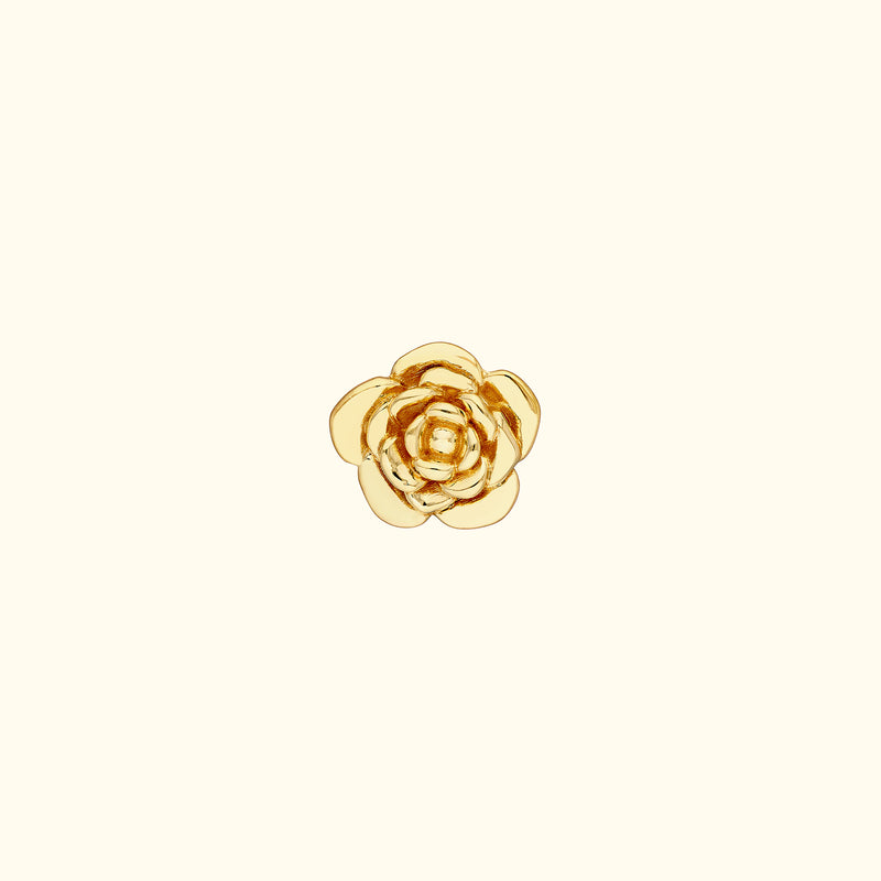 Gold flower-shaped ring with layered petals on a light background.