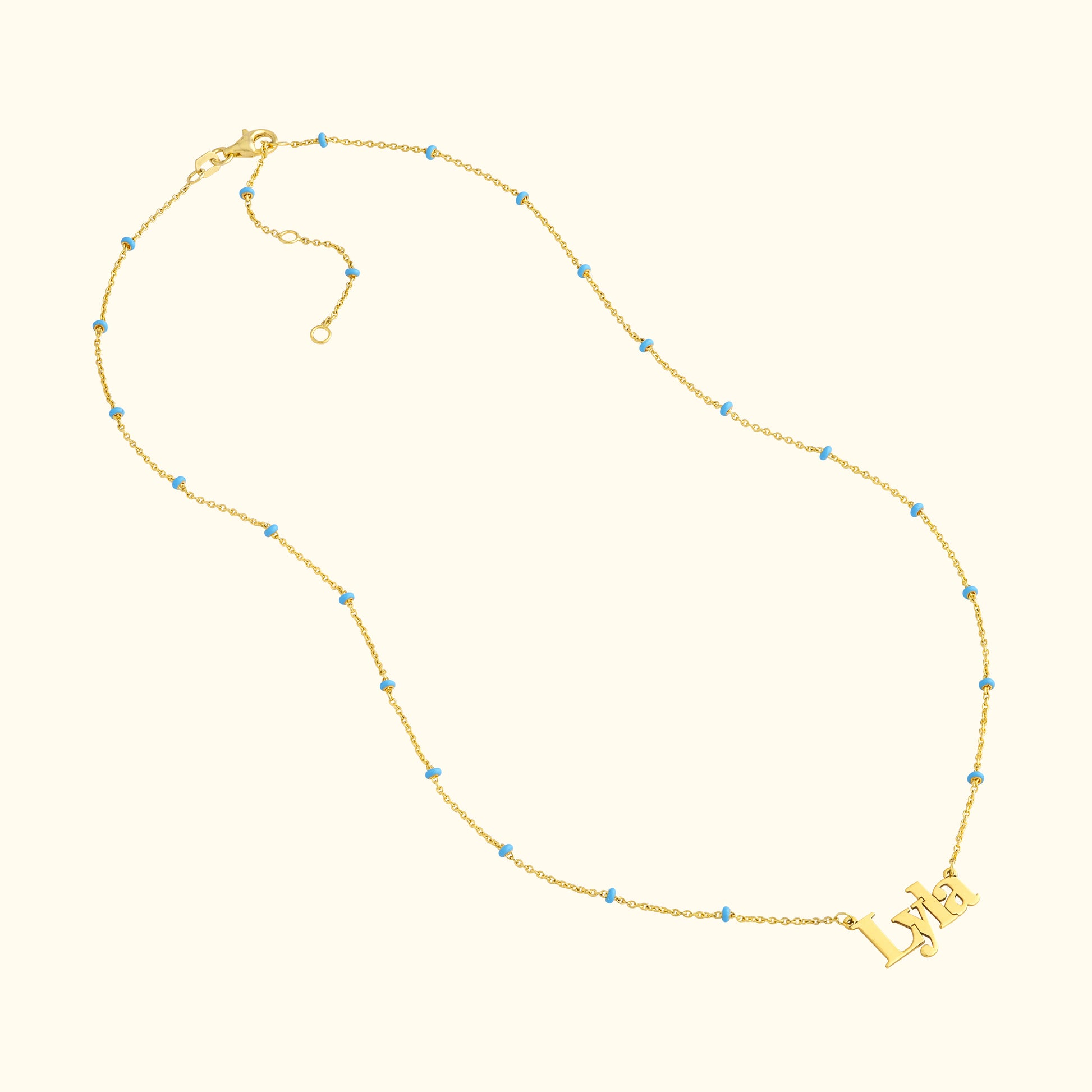Gold necklace featuring the name "Lydia" with blue bead accents.