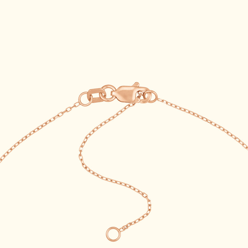 Rose gold necklace clasp with chain detail against a light background.