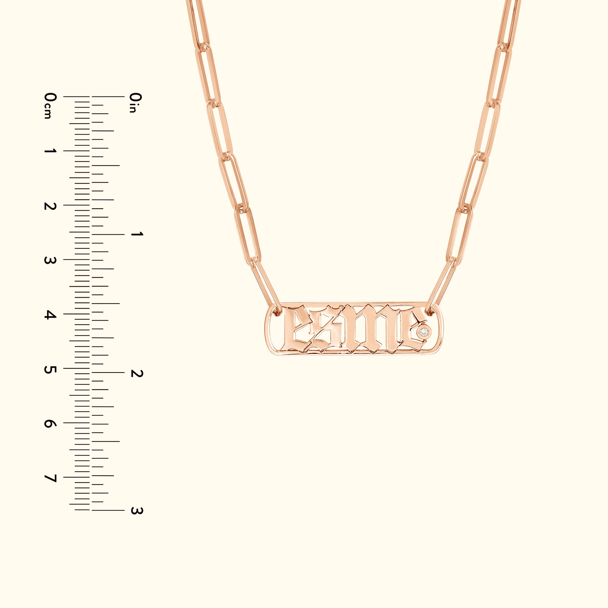 Rose gold chain necklace with a rectangular nameplate and decorative font.