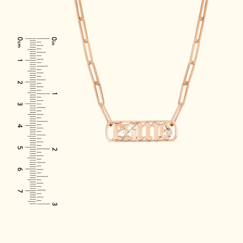 Rose gold chain necklace with a rectangular nameplate and decorative font.