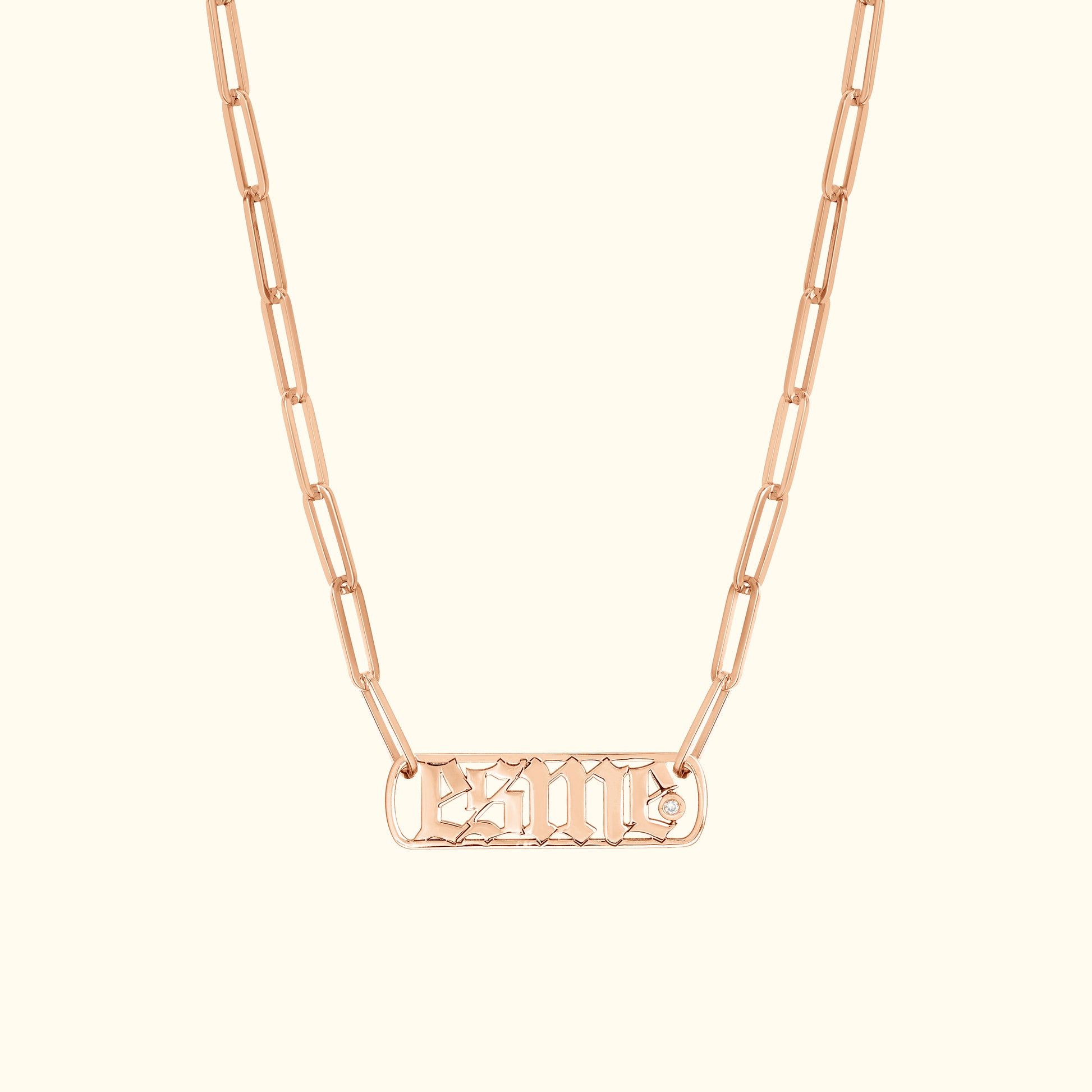 Rose gold chain necklace with a rectangular pendant featuring engraved lettering and a diamond accent.