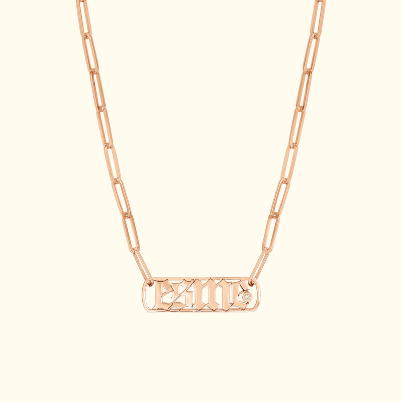 Rose gold chain necklace with a rectangular pendant featuring engraved lettering and a diamond accent.