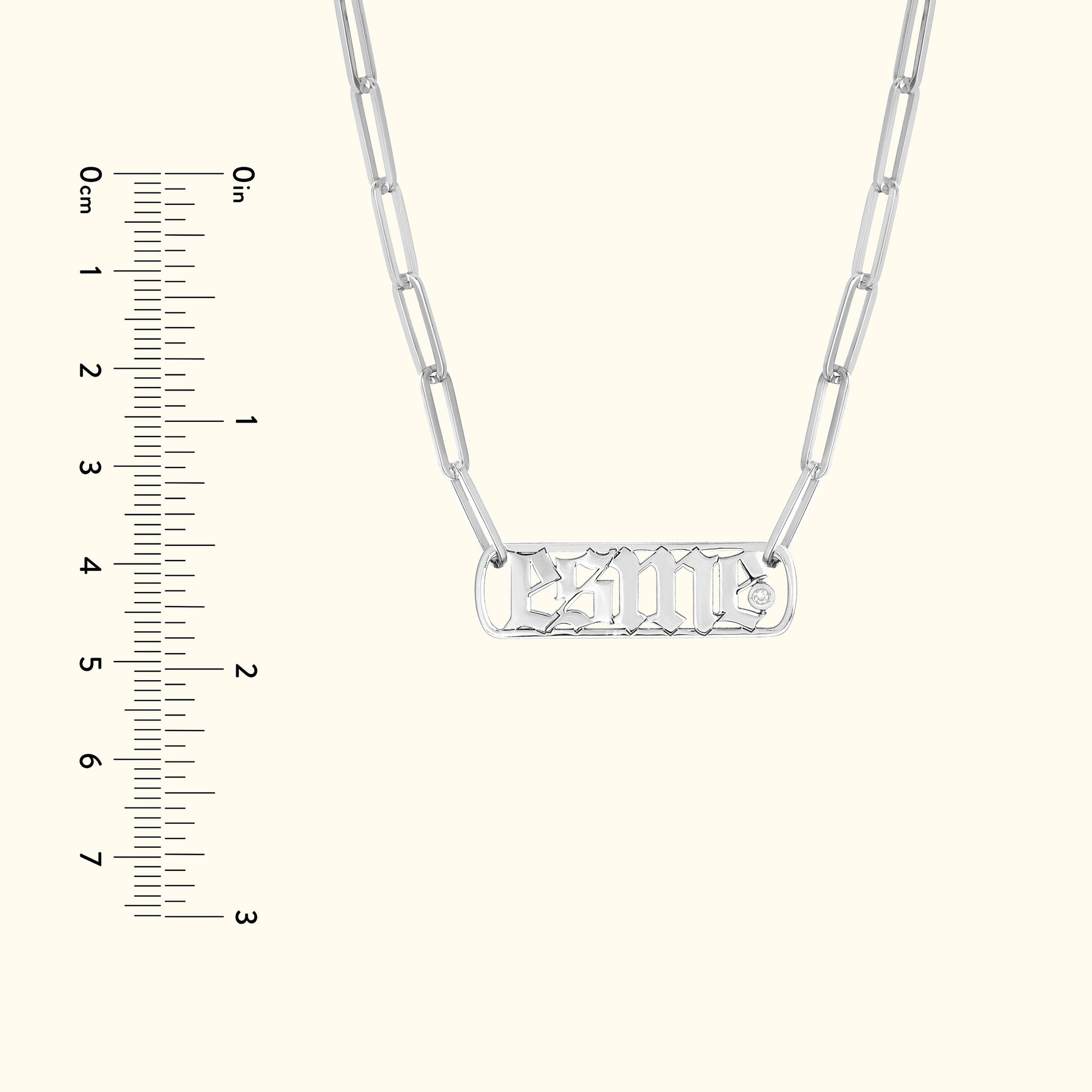 Silver necklace with a rectangular pendant displaying a stylized inscription.