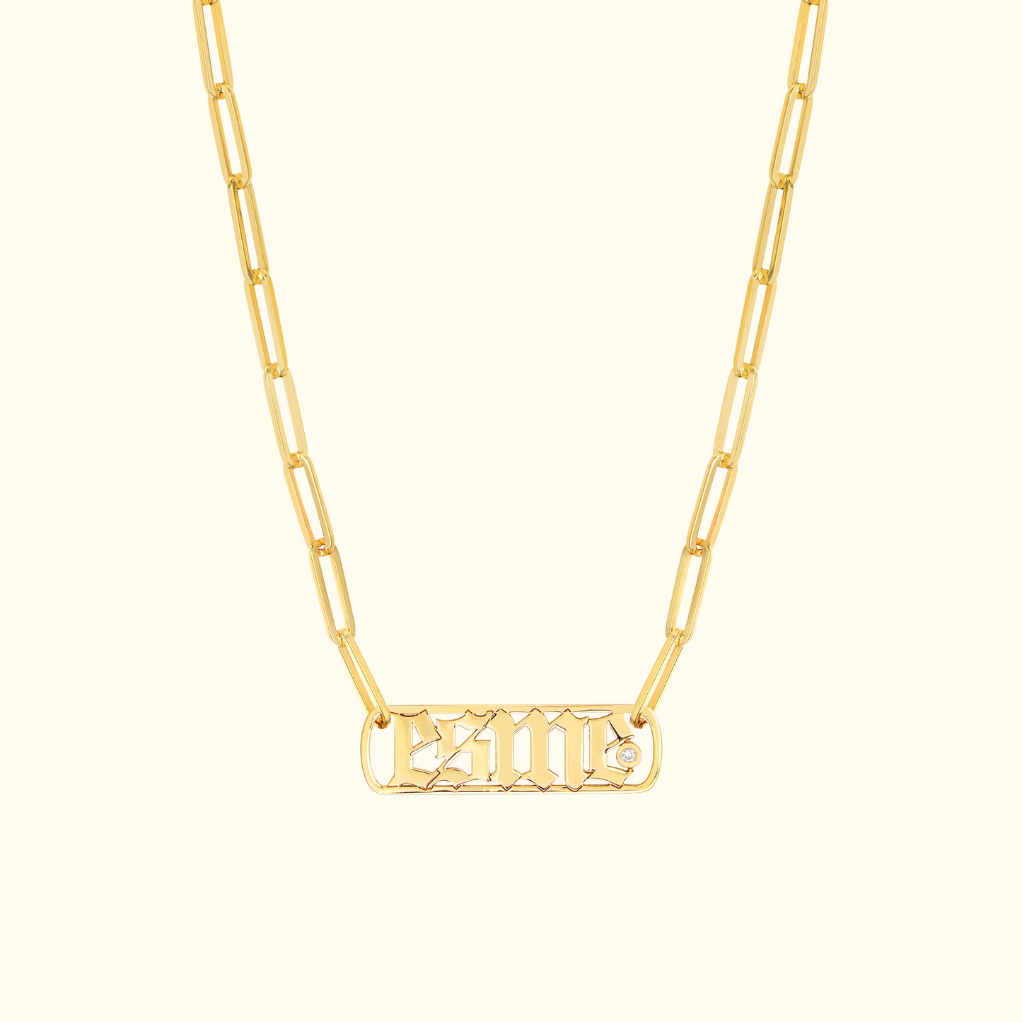 Gold chain necklace featuring a rectangular pendant with engraved letters and a small diamond.