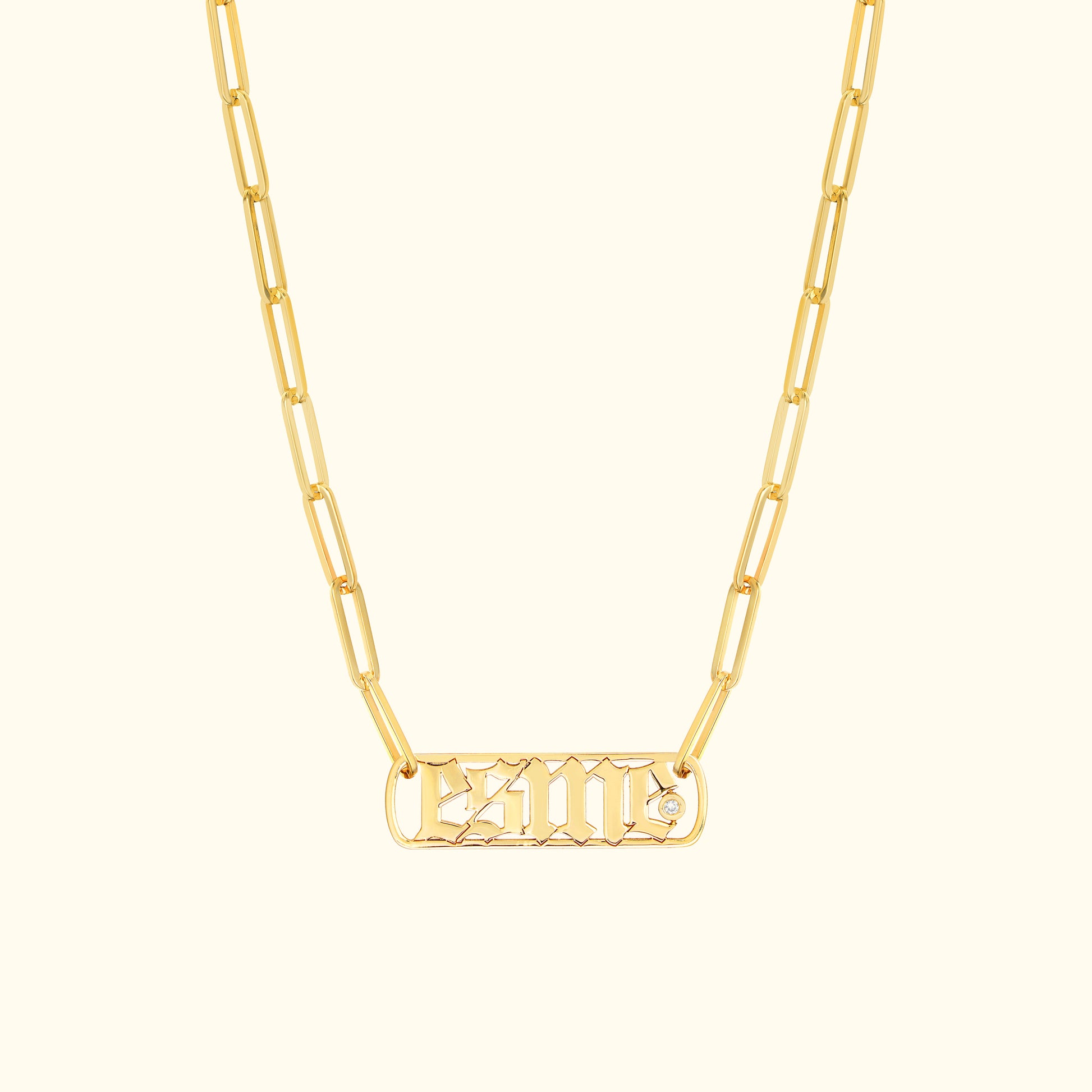 Gold chain necklace featuring a rectangular pendant with engraved letters and a small diamond.